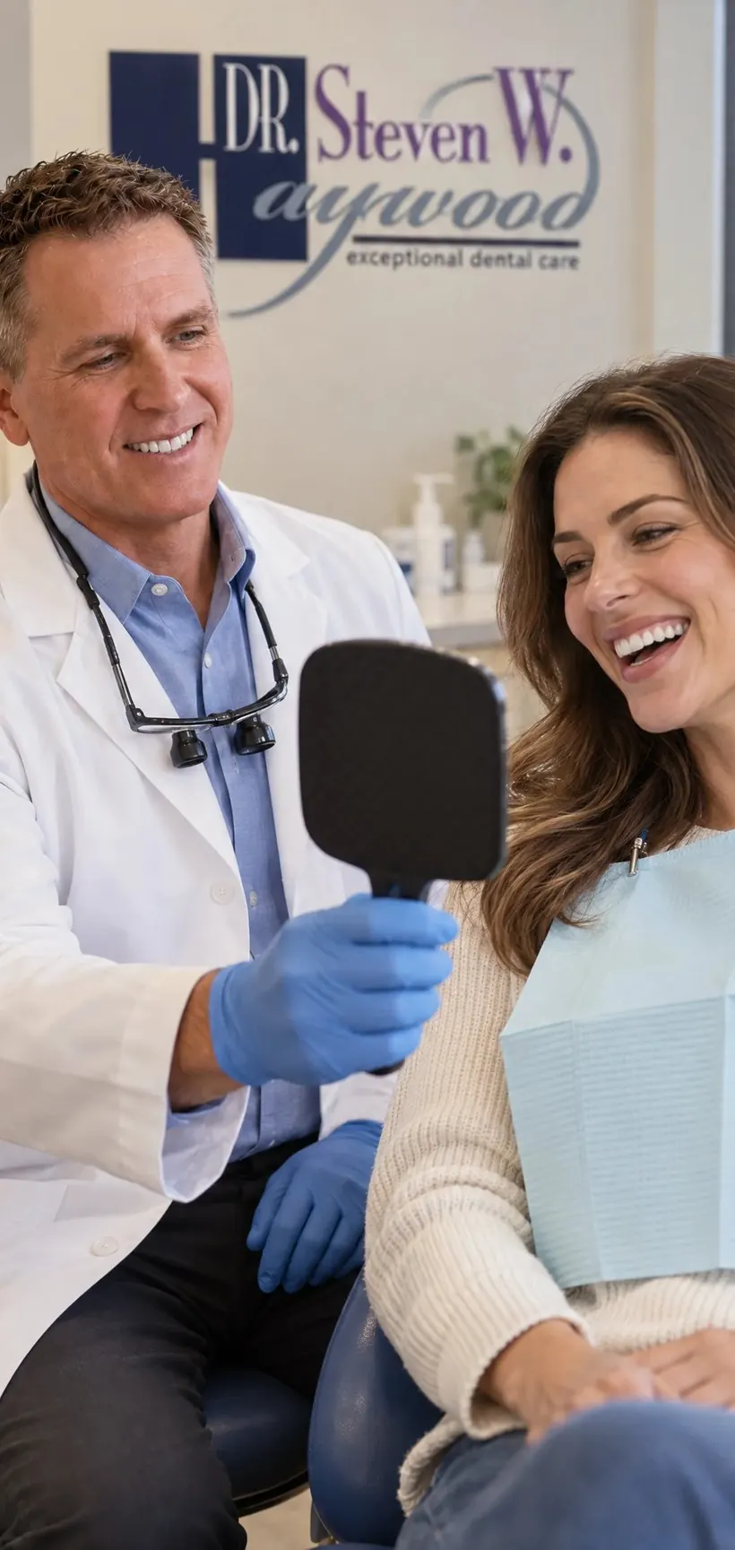 Dr. Steven W. Haywood, DDS showing a patient her new smile in a hand mirror