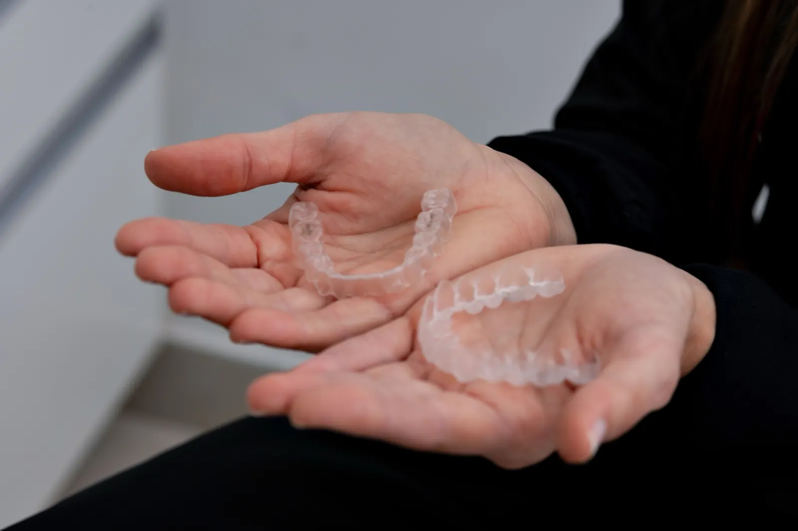A pair of clear aligners held in the hand
