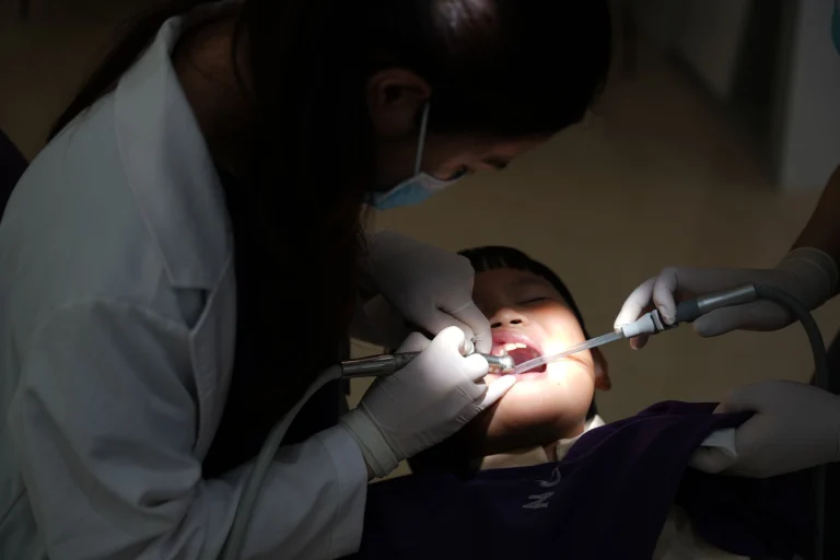 A young child undergoing a dental procedure in a clinic, with a dentist attending.
