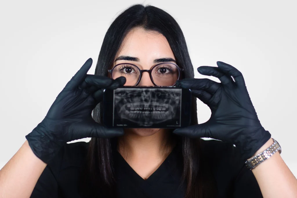 Female dentist holding a dental X-ray displayed on a smartphone, promoting oral health awareness.