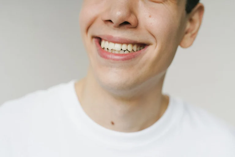 A close-up shot of a young man smiling, highlighting his teeth and expression.