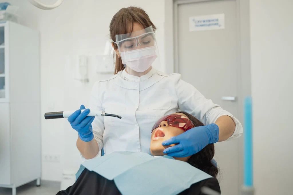 A female dentist using curing light on a patient in a modern dental clinic.