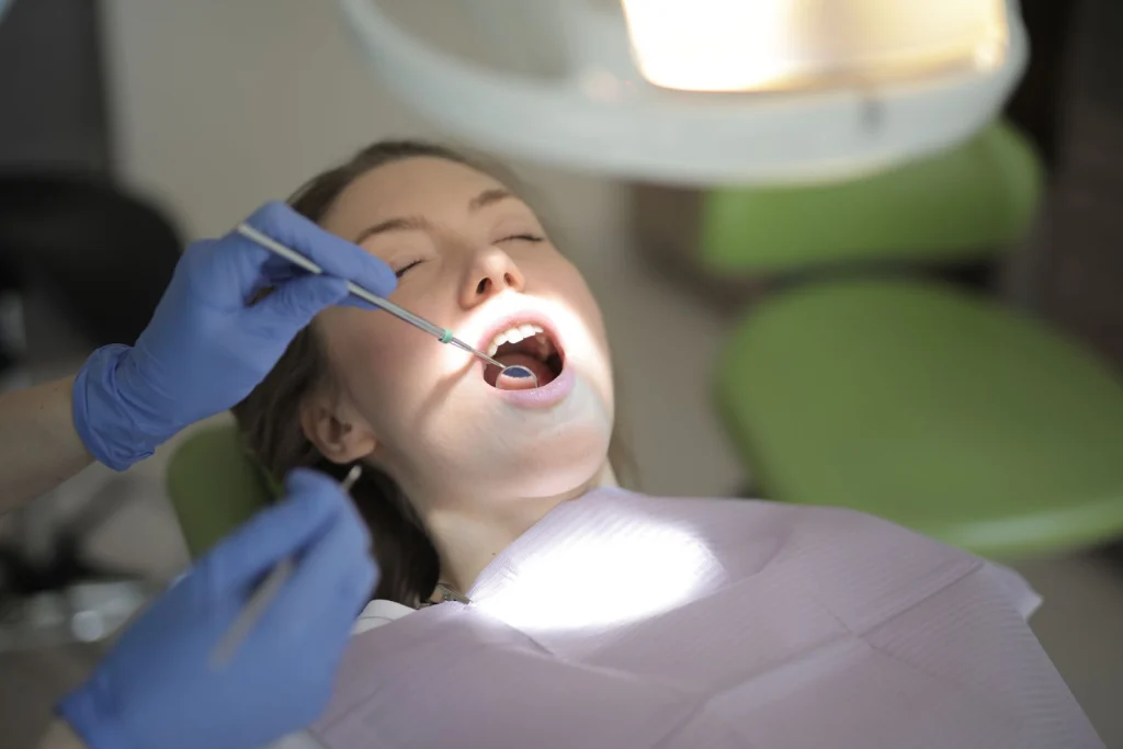 From above view of crop unrecognizable dentist in latex gloves using medical instruments while examining teeth of patient during work in modern dental room