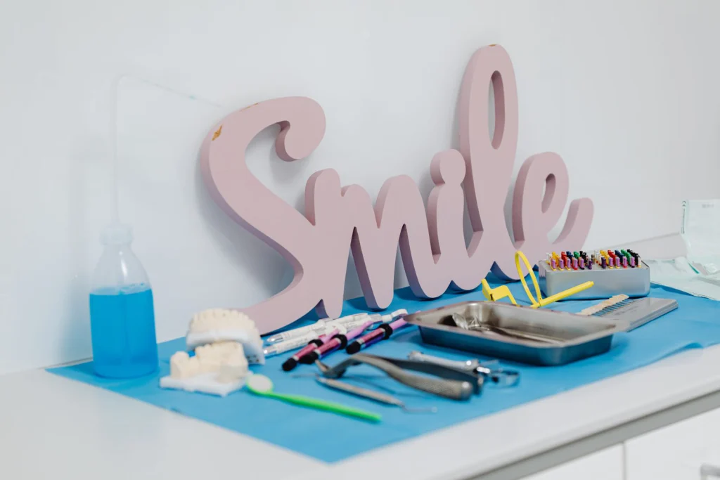 Collection of dental instruments on clinic desk, featuring a 'Smile' decor piece, promoting oral care and hygiene.