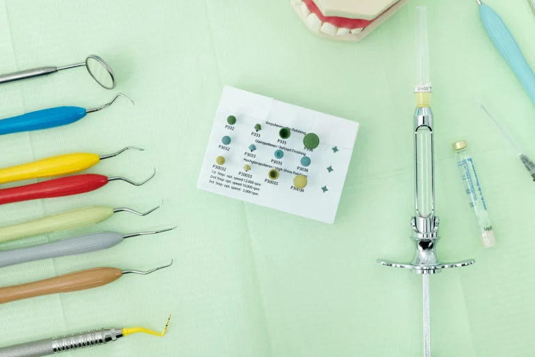Close-up of colorful dental tools and materials arranged on a green surface for dentistry.