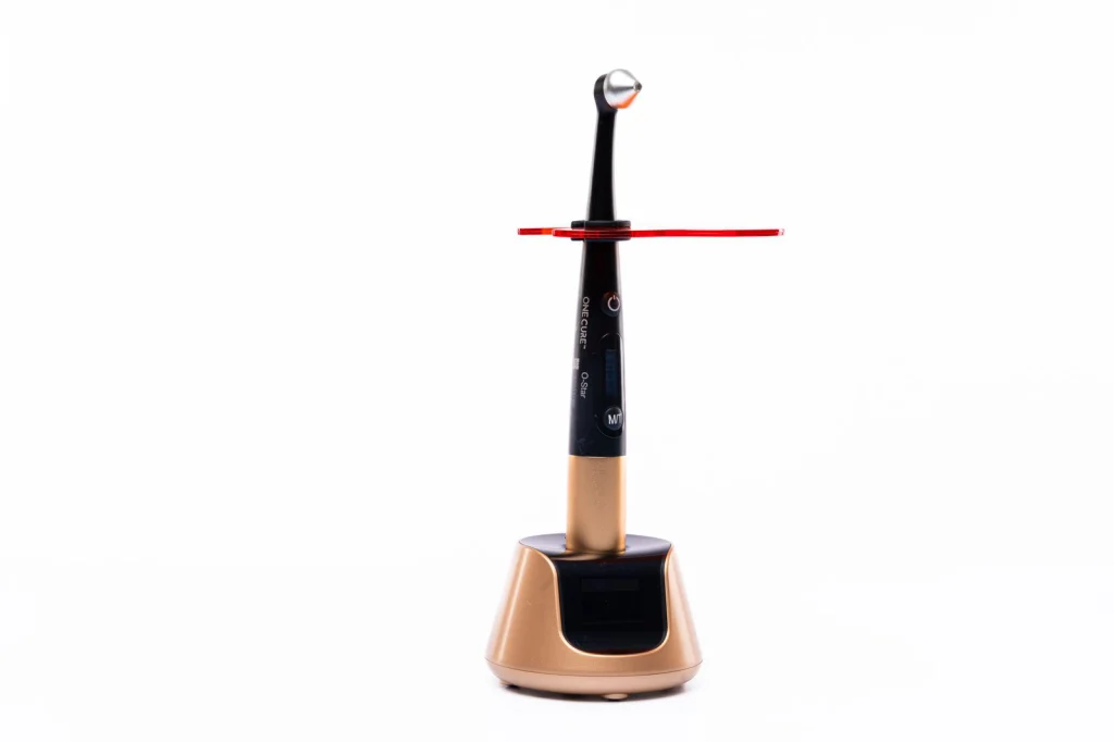 High-tech dental curing light with sleek black and gold design on a white background.