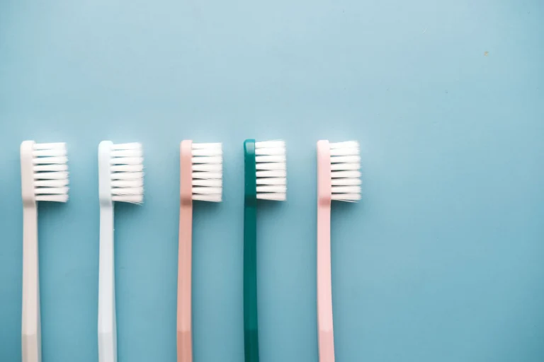 A row of five colorful toothbrushes arranged on a blue background, perfect for dental care themes.