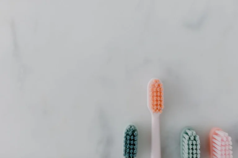 A clean and simple flat lay of four colorful toothbrushes on a marble surface.