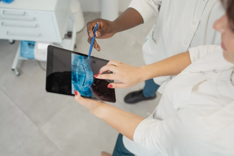 Dentist examining a dental x-ray on a tablet with patient in a modern clinic.