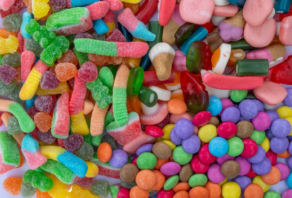 A vivid collection of assorted gummy worms, jellybeans, and candy-coated chocolates.