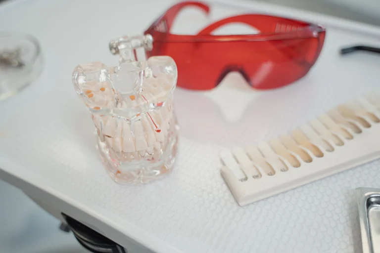 Dental cast, shade guide, and safety glasses on a clinical tray for dental procedures.