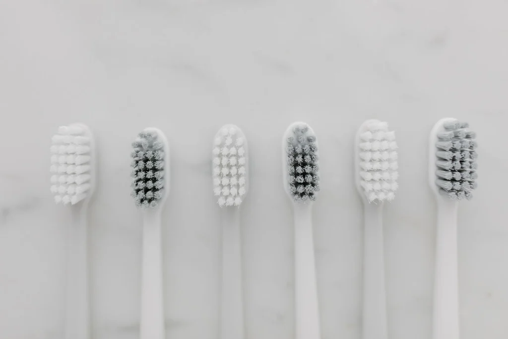 A clean, minimalist top view of six white toothbrushes on a marble surface.
