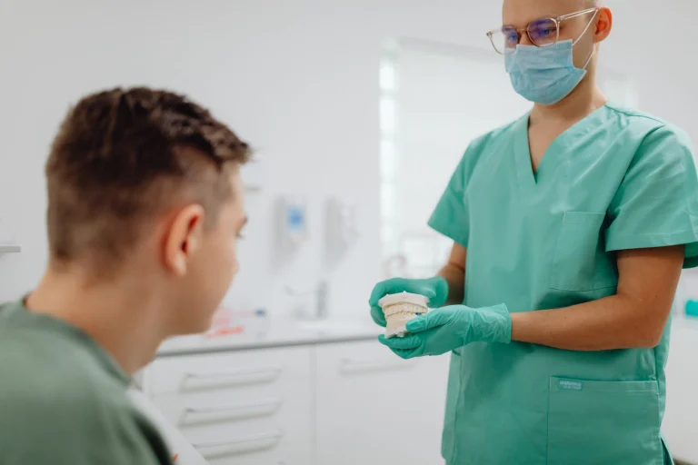 Dentist discussing treatment options with patient using dental model.